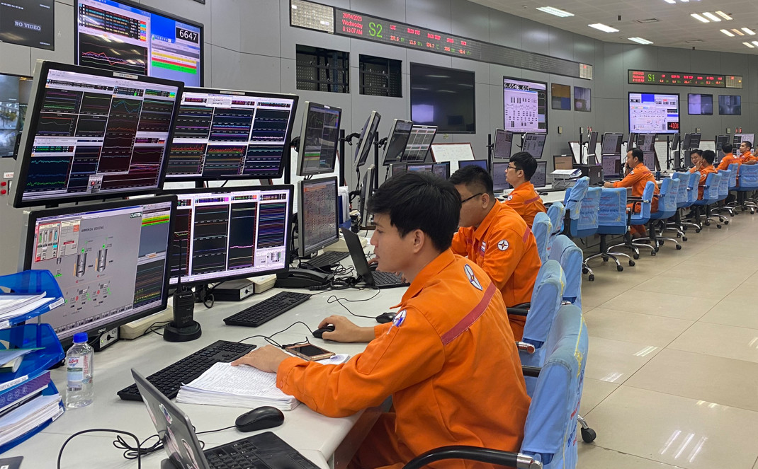 A group of people in orange jumpsuits sitting at a deskDescription automatically generated