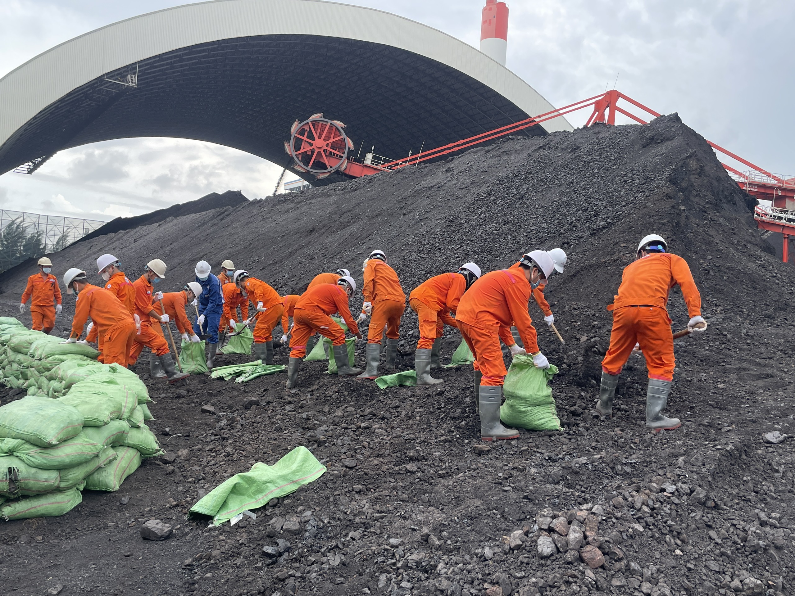 A group of people in orange jumpsuits and white helmetsDescription automatically generated