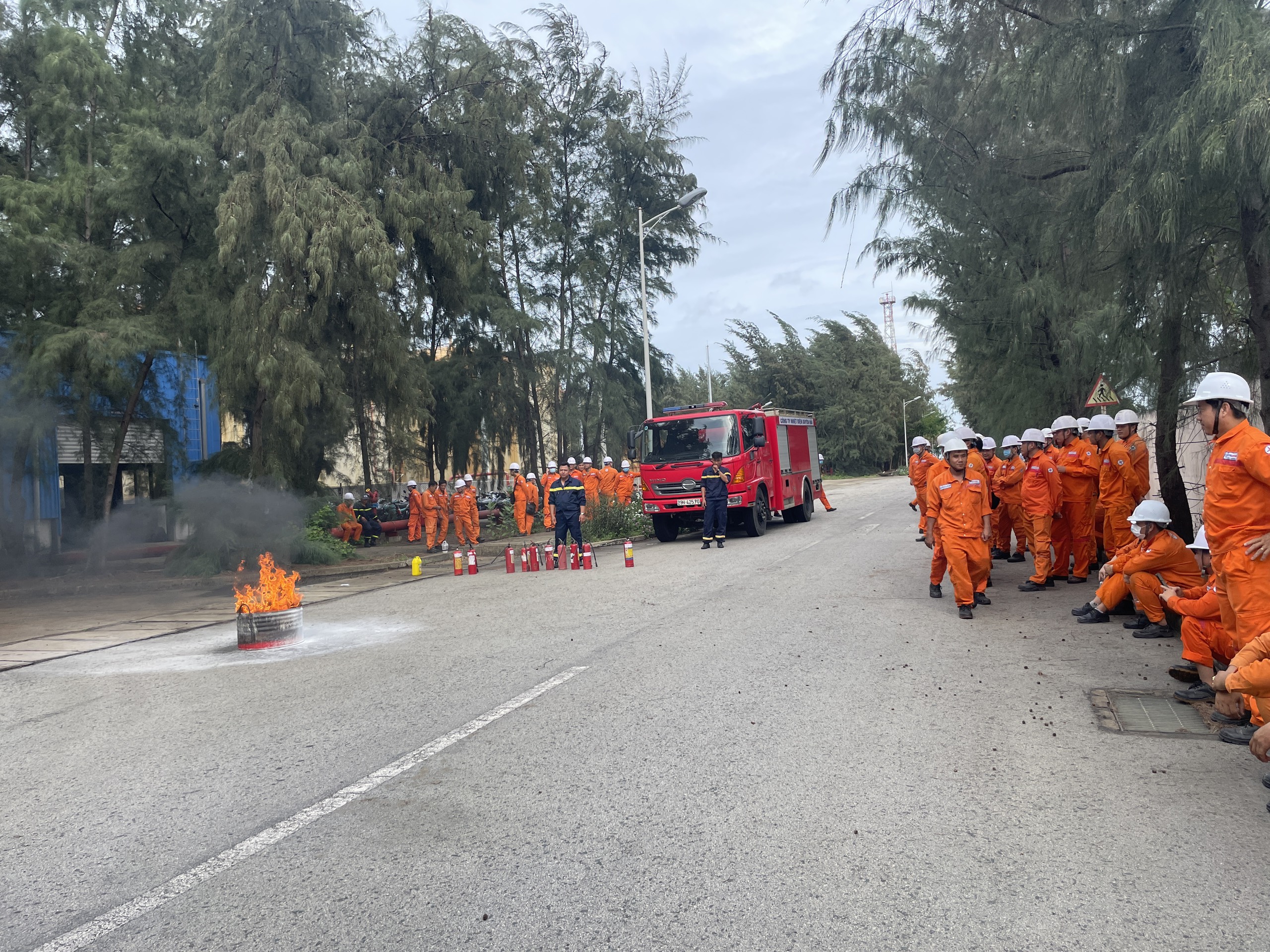 A group of firefighters standing on a roadDescription automatically generated